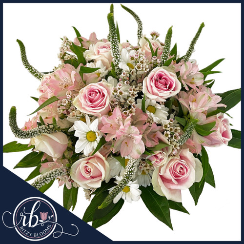 Blush Elegance Baby Floral Arrangement with pink roses, daisies, greenery in a ceramic vase, featuring a satin bow and butterfly accent.