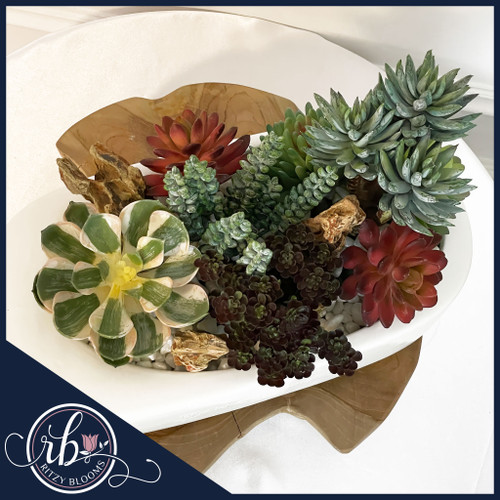Faux succulent arrangement in a white oval planter with natural pebbles and dragon stones, available at Ritzy Blooms in Fort Lauderdale, FL.