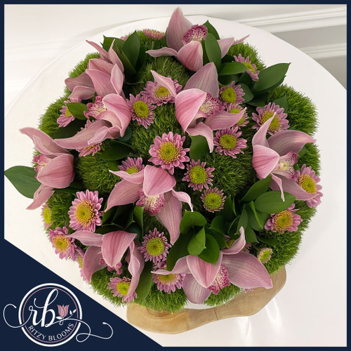 Elegant cymbidium orchid and daisy centerpiece in silver bowl