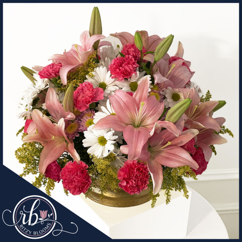 Cheerful pink lily, carnation, and daisy floral centerpiece in a gold bowl by Ritzy Blooms Fort Lauderdale