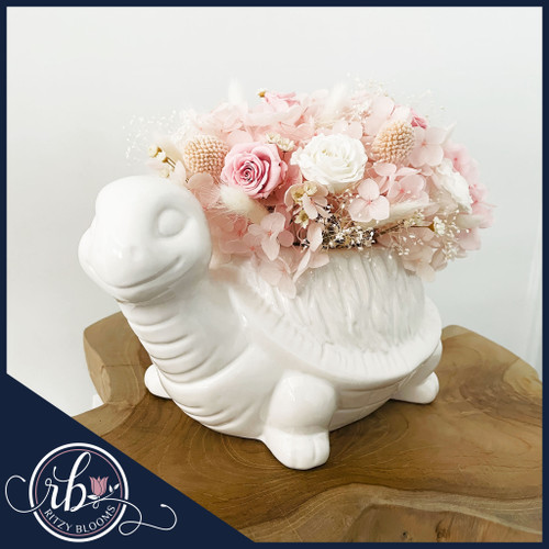Petite blush preserved floral arrangement in a white ceramic turtle vase, handcrafted by a Fort Lauderdale florist for bedroom and nursery decor.