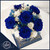 Elegant floral arrangement in a white round box from Ritzy Blooms, featuring preserved royal blue and white roses accented with delicate white and blue filler flowers, placed on top of a beautifully designed blue and gold hardcover book. Crafted by Ritzy Blooms in Fort Lauderdale.