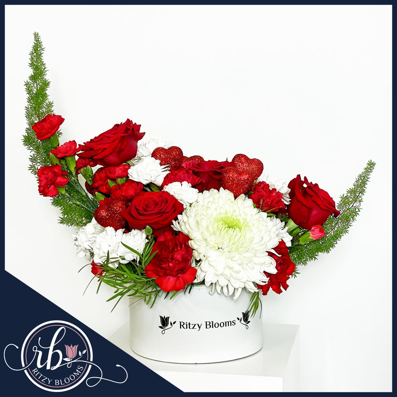 Crescent Heartfelt Affection flower arrangement featuring red roses, carnations, white blooms, and sparkling heart accents in a Ritzy Blooms hatbox. Crafted by Ritzy Blooms