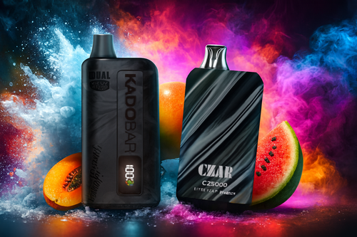 The photo shows two PACHA MAMA vape devices set against a vibrant, cosmic-inspired background of pink, blue, and purple splashes. The left device, labeled “PACHA MAMA STORM 25W,” is black and orange with a digital display showing battery and e-liquid levels, while the right, “PACHA SY77,” features a smooth gradient from blue to green. Surrounding them are slices of orange, watermelon, apple, strawberry, lychee, and scattered ice cubes, emphasizing refreshing fruity flavors. The overall composition feels energetic and modern, designed to highlight both flavor variety and sleek design.