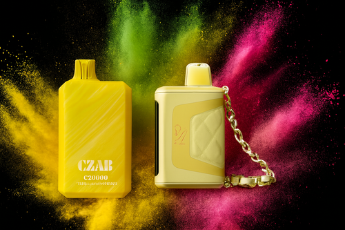 The photo shows two bright yellow vape devices set against a vivid background of colored powder bursts in shades of yellow, green, and pink. The device on the left is rectangular with a smooth surface and the text “CZAB C20000” printed on it, while the device on the right has a more intricate design featuring a quilted texture, a metallic chain, and a mouthpiece. The bold colors and dynamic composition create a striking, energetic atmosphere that highlights the modern and stylish look of the products.