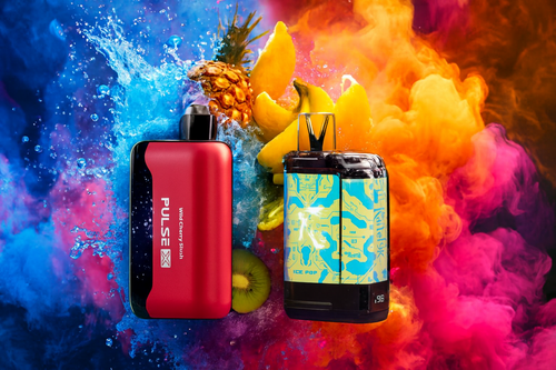 The photo shows two colorful vape devices placed against a vibrant background of splashing water and swirling clouds of orange, pink, and purple. Behind them are fresh fruits like pineapple, bananas, and kiwi, emphasizing a fruity flavor theme. The device on the left is red and black, labeled “PULSE X” with the flavor “Wild Cherry Slush,” while the one on the right has a blue and yellow circuit-like design marked “ICE POP” and a digital display showing “9.8.” The dynamic composition and vivid colors highlight both the flavor appeal and modern design of the products.