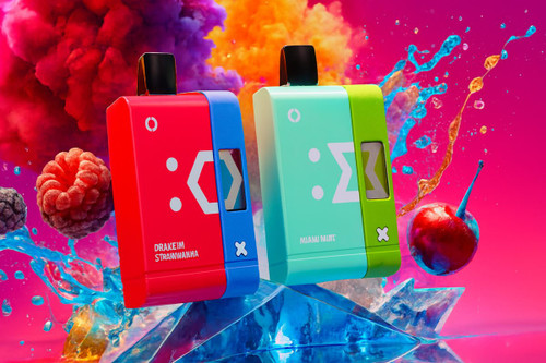 Two dual-tone rectangular vapes, one red and blue and the other mint and green, stand upright on a jagged crystalline surface. Vibrant splashes of liquid, fresh fruit, and plumes of orange and purple smoke surround the devices against a bright pink backdrop. The design features bold minimalist graphics and a small digital screen on the side of each unit.