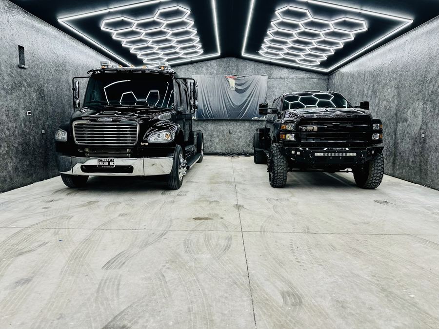 Garage bay with hexagon lighting and two black trucks