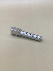 Silver Glock 19 Gen 1-5 barrel shown at an angle on a light background, highlighting its ported design and extended profile.

Angled view of a stainless steel 9mm ported pistol barrel on a light surface.