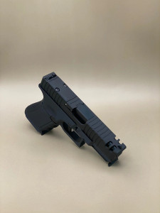 Angled view of the Kineti-Tech Phantom Complete Slide installed on a Glock‑style frame, showcasing the bull‑nose front profile, deep‑cut forward and rear serrations, and front lightening ports. The CERAKOTE® finish and RMR® optic cut are clearly visible, highlighting the slide’s aggressive duty‑ready design.

Kineti-Tech Phantom Black Slide for Glock 19 Gen 3 shown at an angle with bull nose cut, serrations, and lightening ports.