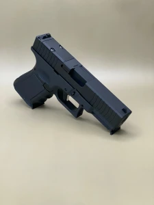 A left-side profile of the Kineti-Tech Serrated Bullnose Complete Slide mounted on a Glock® 19 Gen 5/19X frame. The Armor Black CERAKOTE® finish is clearly visible, along with deep-cut front and rear serrations. The slide is shown against a neutral background, emphasizing its rugged design and optic-ready rear cut.

Left-side view of Kineti-Tech Serrated Bullnose Slide for Glock 19 Gen 5/19X with deep serrations and black CERAKOTE® finish.