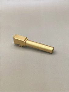 Angled side view of a Gold TiN‑coated Glock 19 Gen 5 barrel displayed on a neutral light background, highlighting the length and overall finish.

Angled photo of a Gold TiN 9mm pistol barrel on a light background.