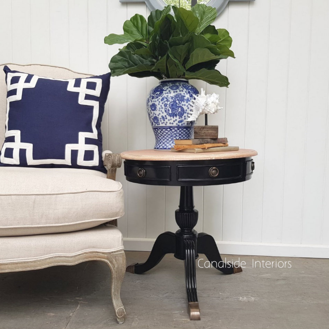Add a touch of sophistication to your guest room with the classic black Cobble Hill Round Table from Canalside Interiors, featuring a unique limewash top for a coastal vibe