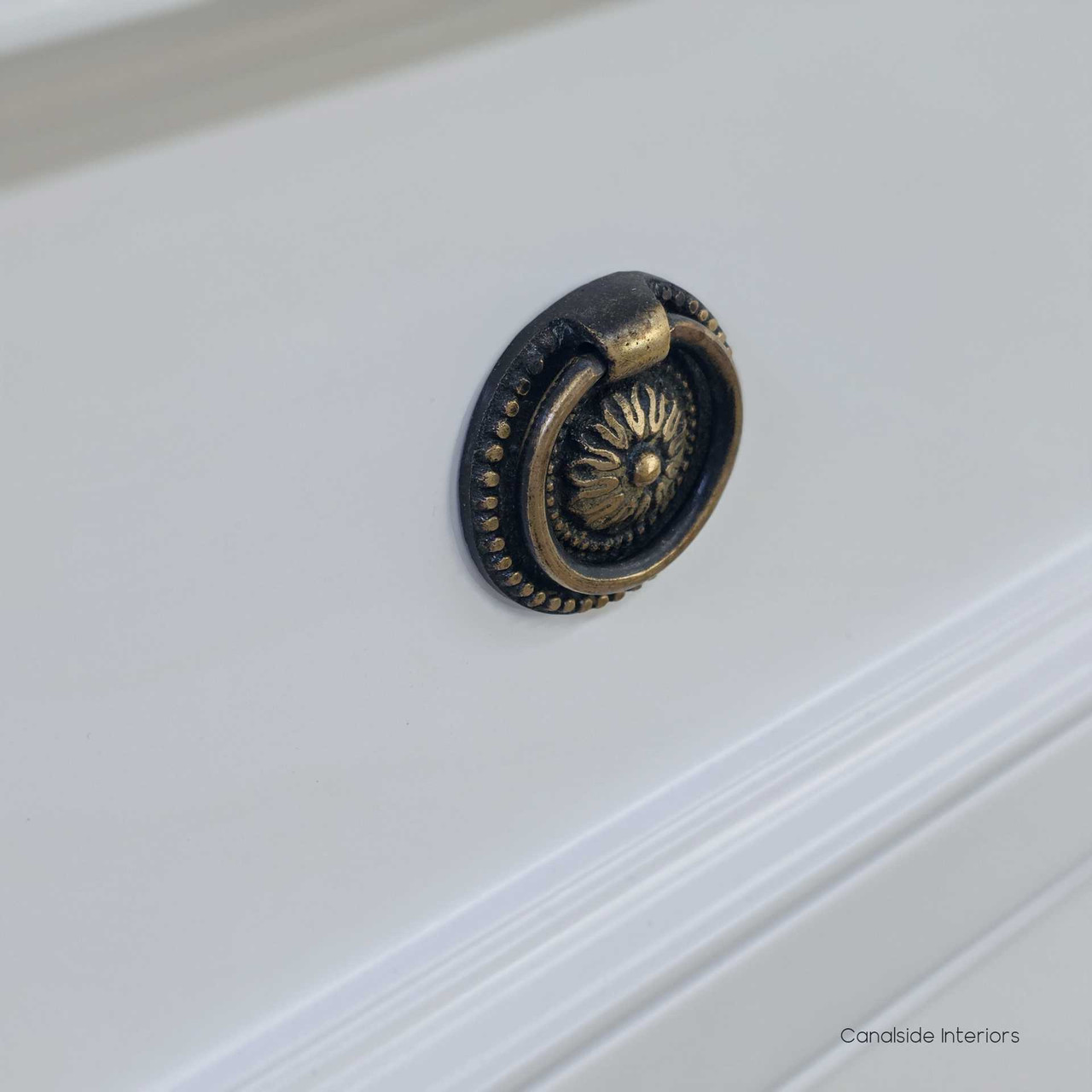 lose-up of the decorative hardware with textured beading on the bright white drawer front.