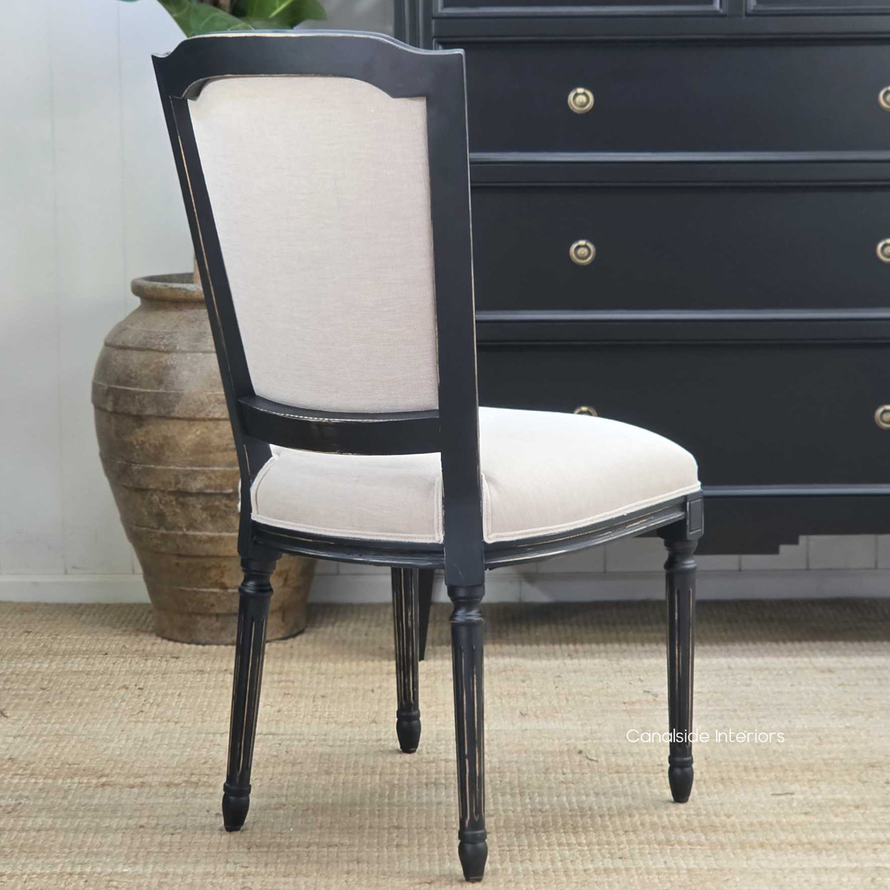 Back three-quarter perspective highlighting the contrast between black frame and cream upholstery.