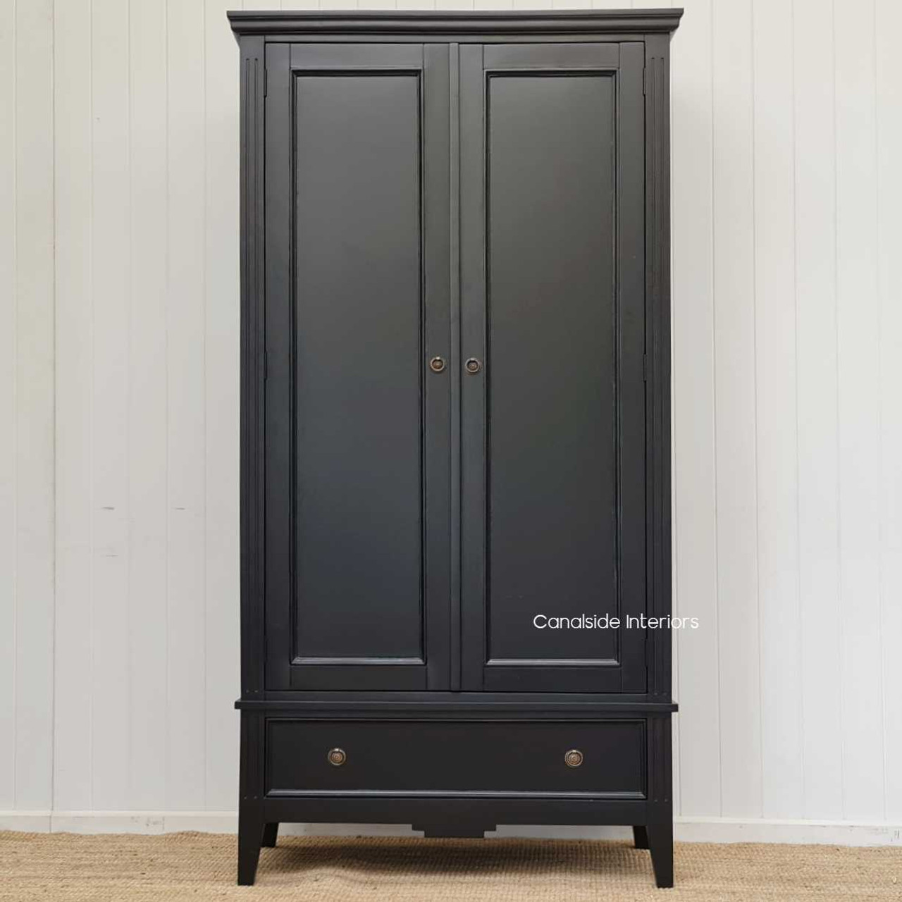 Set against a vivid white wall color, the black finish of the wardrobe stands out, complementing various interior color schemes.
