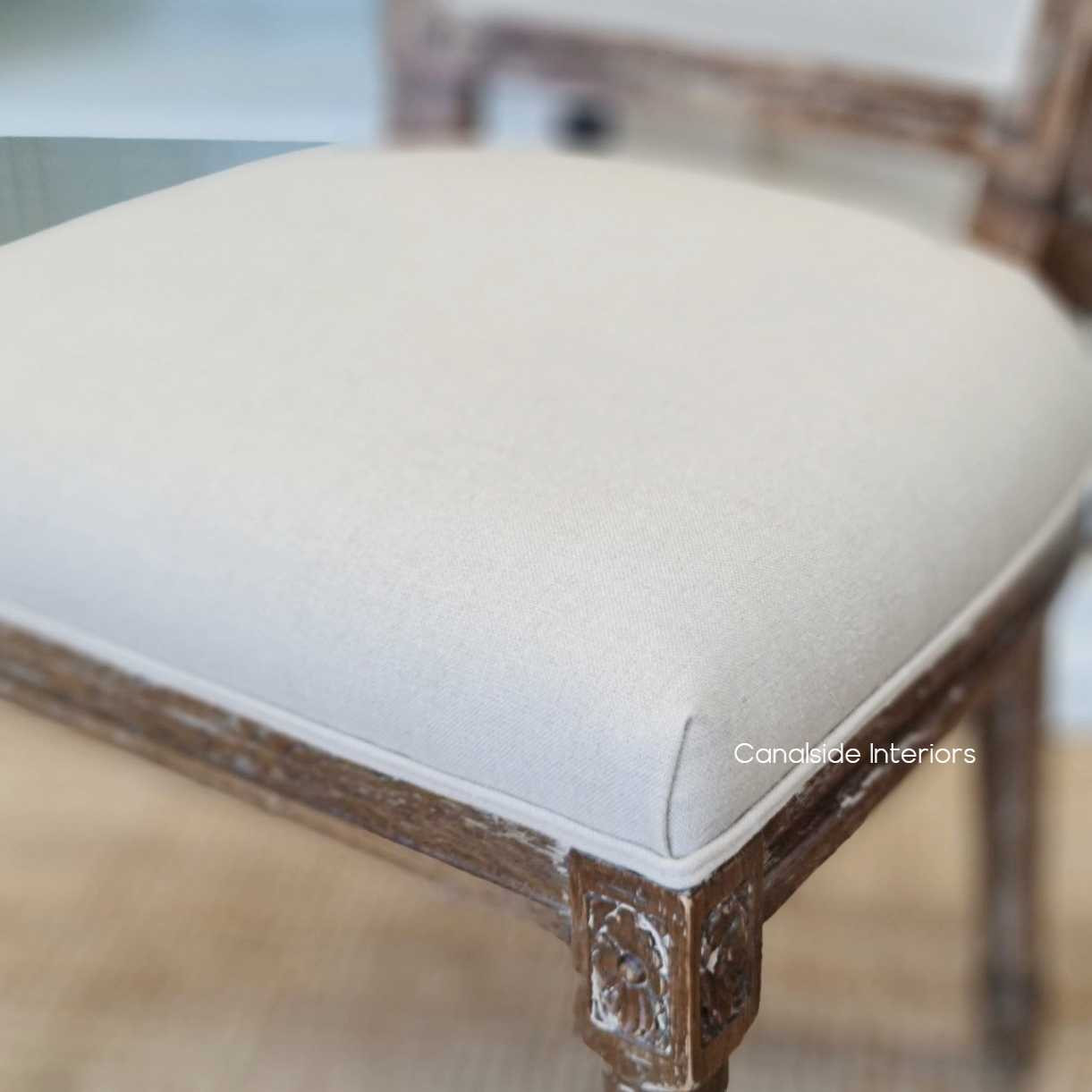 Elegant and versatile, this chair's timeless design and cream upholstery complement any library or home office setting - Canalside Interiors.