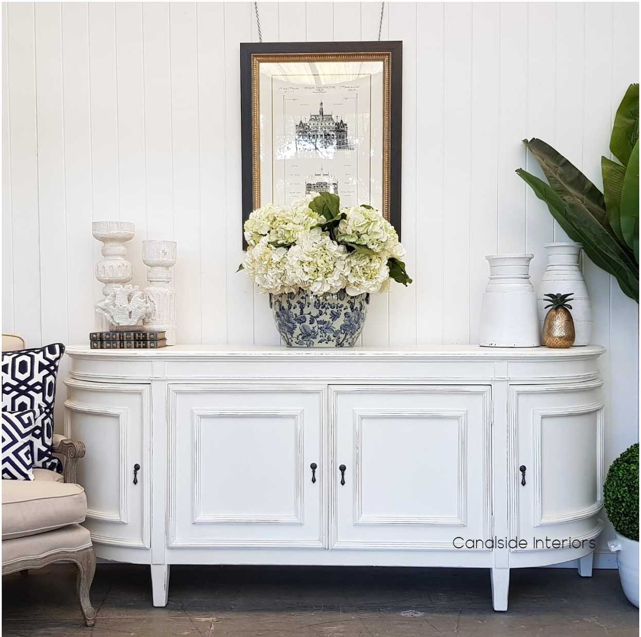 In a library setting, the Francia Sideboard in distressed off white anchors the room with its traditional silhouette, complementing both colonial plantation and provincial styles