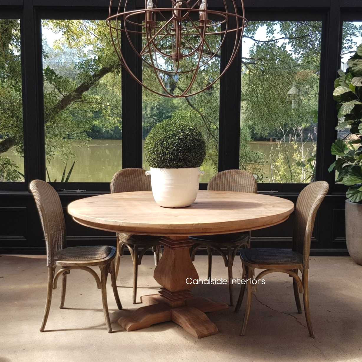 The Artisan Round Dining Table under natural lighting, accentuating the wood's warm tones and enhancing the room's ambiance.