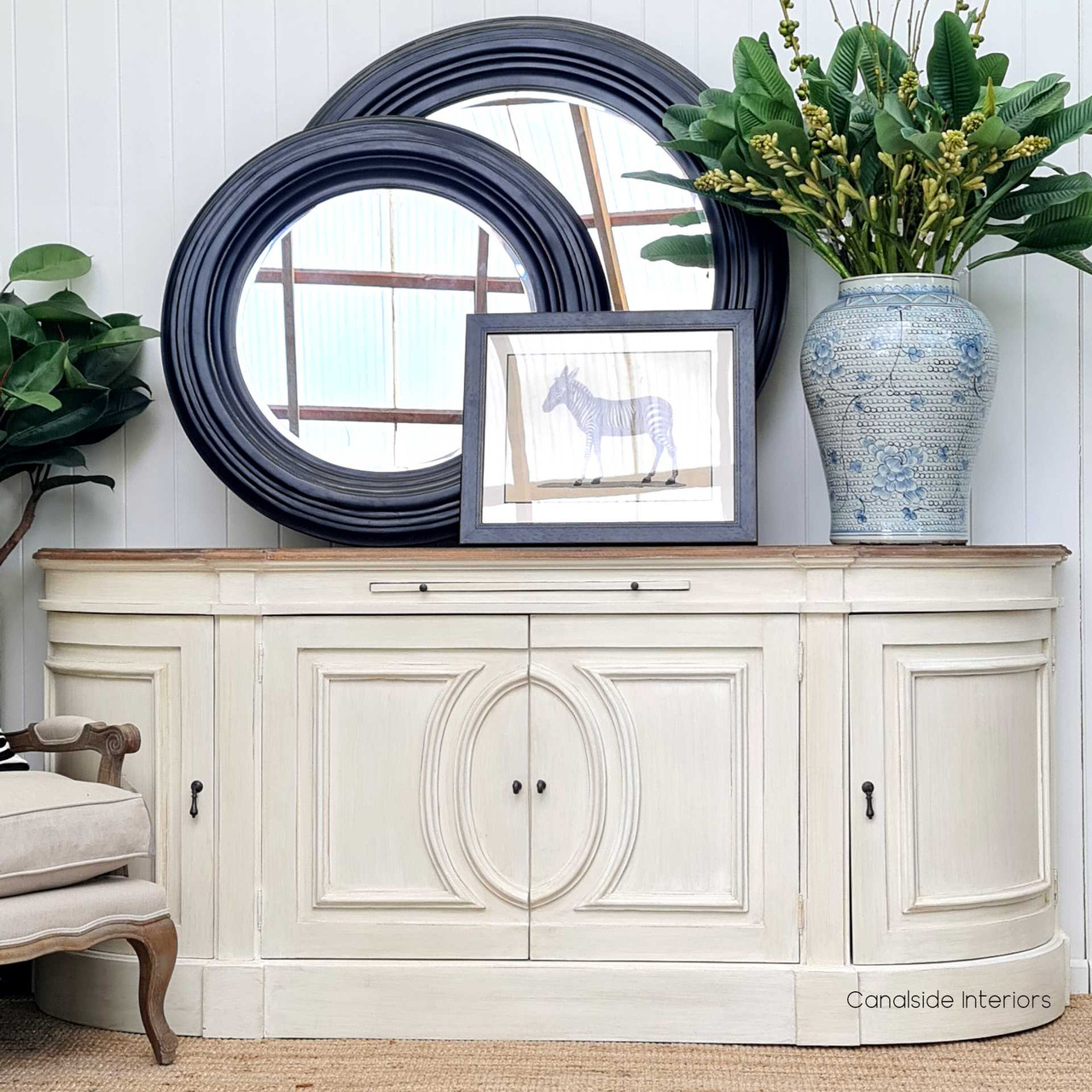 The Bastian Large Sideboard's stone finish and weathered oak top blend traditional French design with a Hamptons-style flair, offering a sophisticated storage solution for your living room