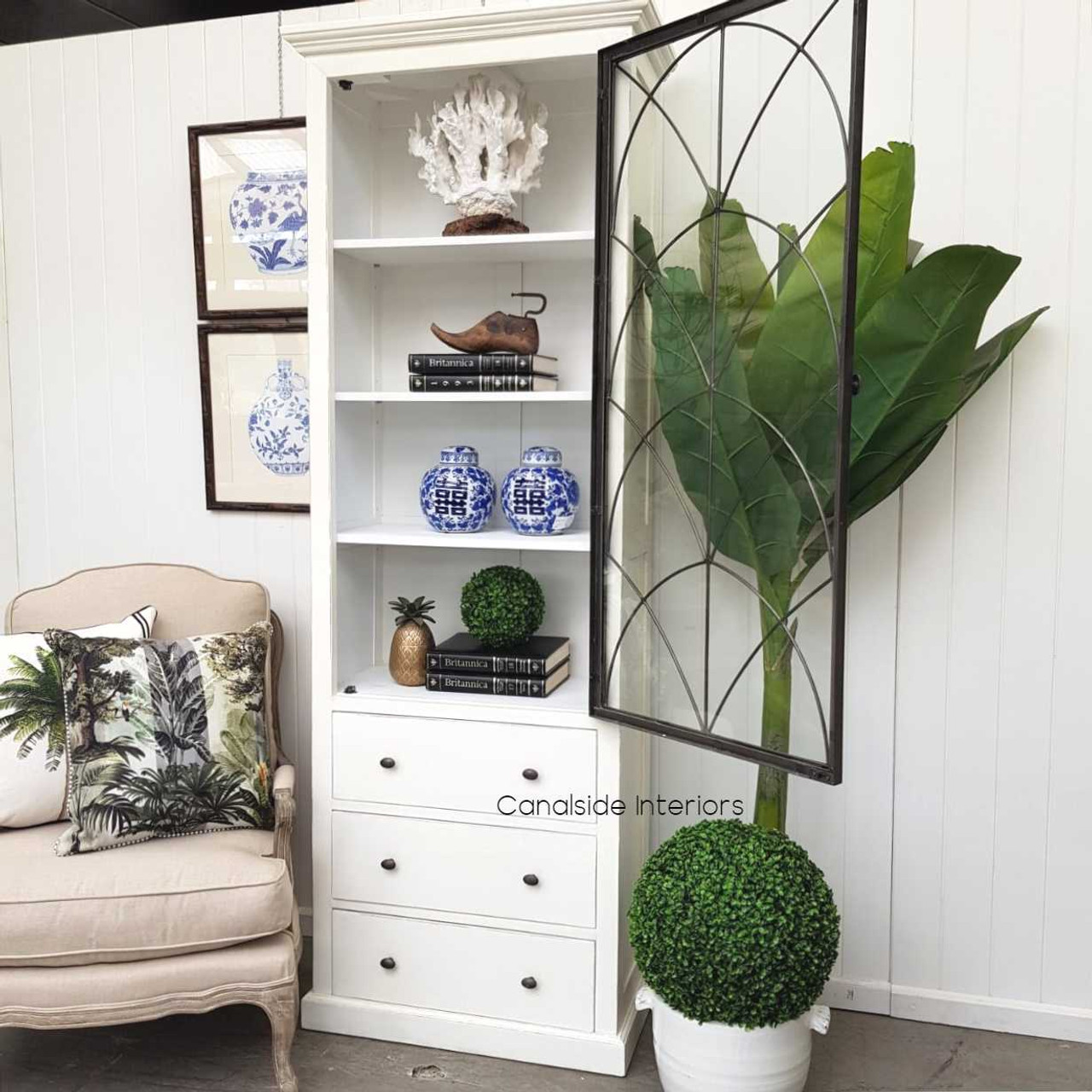 Angled shot of the Wessex Cabinet, highlighting the contrast between its distressed white exterior and the treasures it holds within.