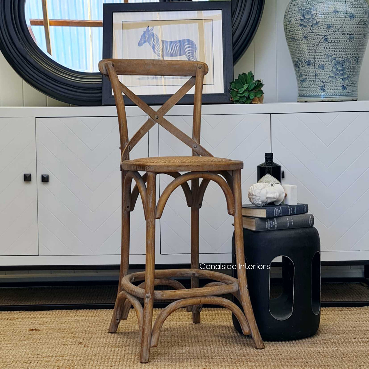 A front-facing image of the Cross Back Stool reveals the stool’s chic, oatmeal patina, integrating seamlessly into classical or modern kitchen decor
