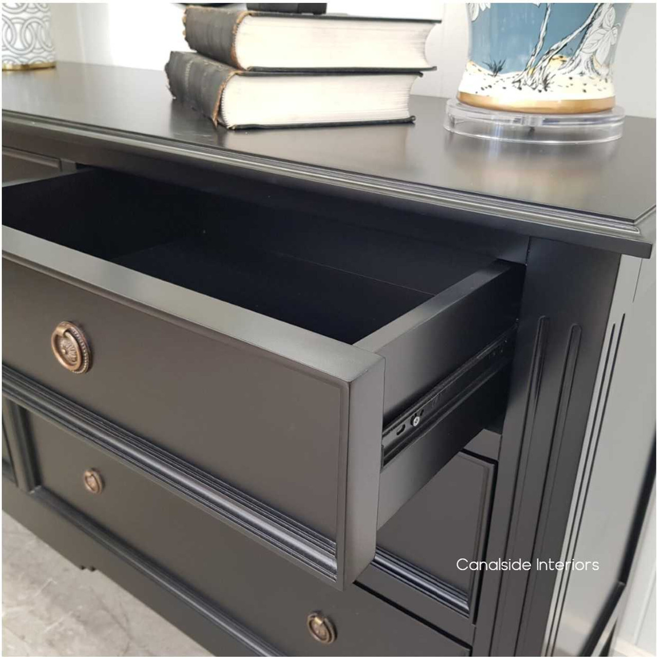 Close-up of the Peninsula black 7-drawer chest sideboard with a drawer open, showing metal drawer runners, internal storage space and quality craftsmanship