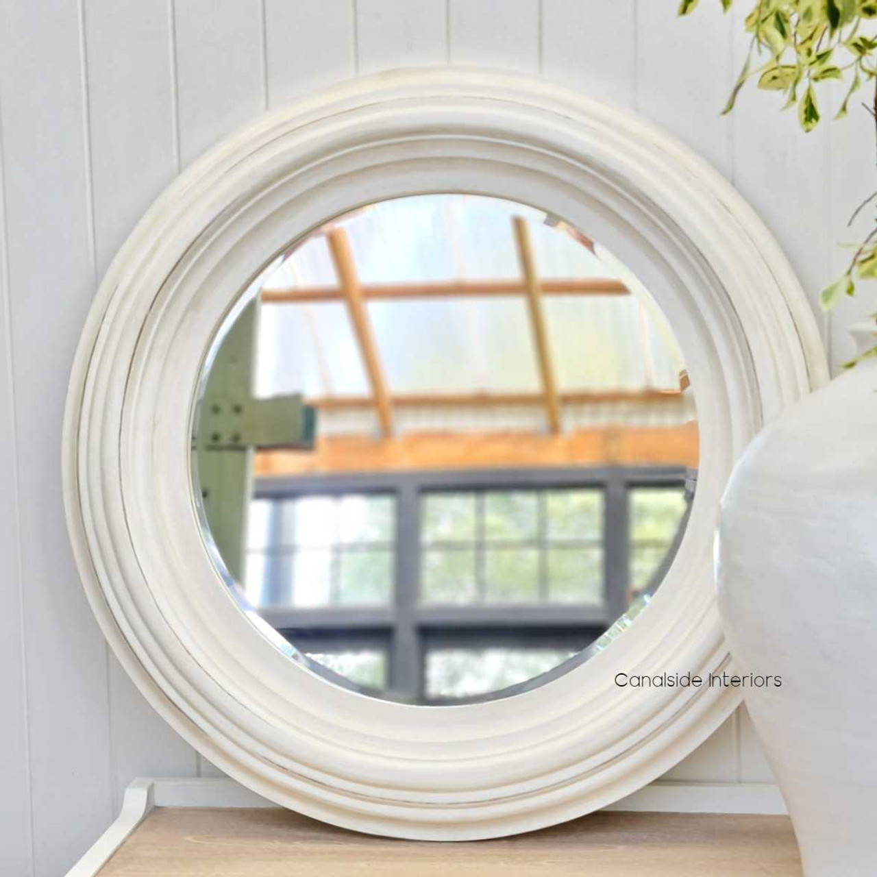 The Aspen mirror under natural lighting, accentuating the warm tones of the distressed white finish and enhancing the ambiance.