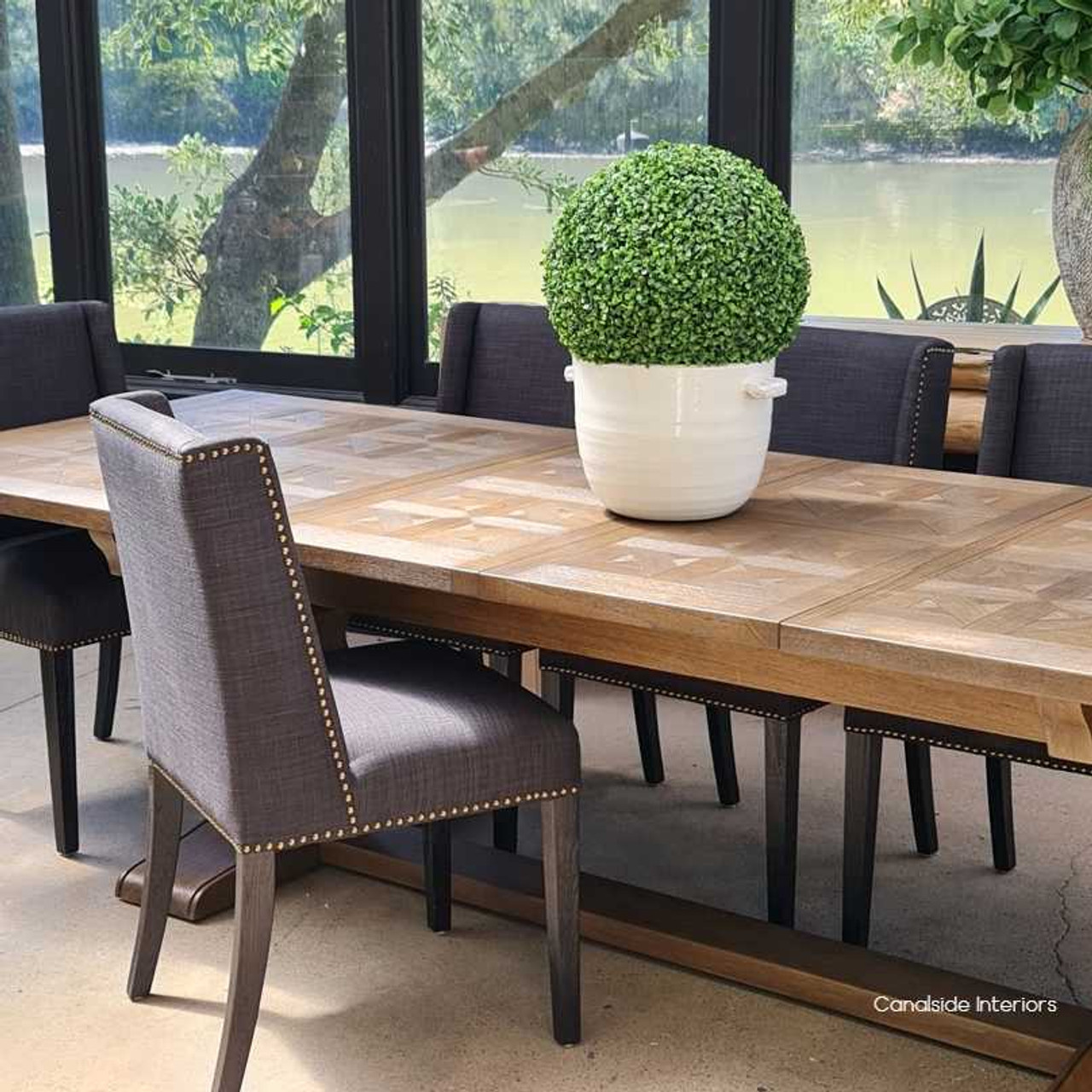 Elevated view of the dining table in a sunlit space, highlighting the natural beauty of the white cedar wood and parquetry top.