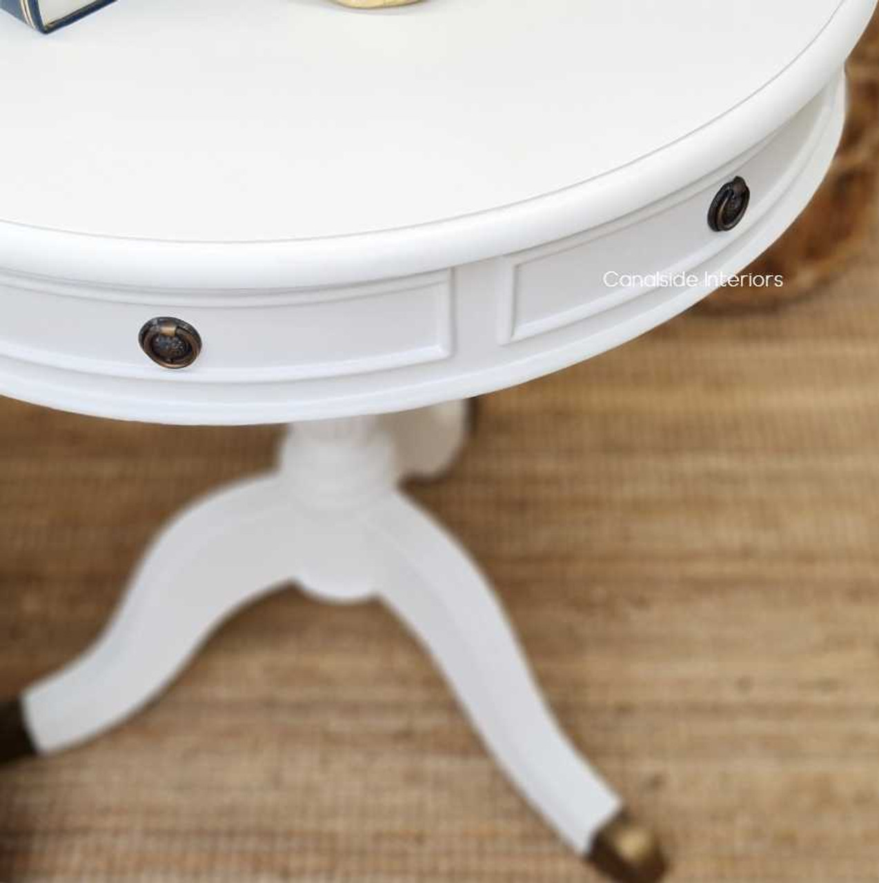 The sophisticated silhouette of the Cobble Hill Large Round Table, featured in distressed white, complements the coastal decor of any lounge room, available at Canalside Interiors.