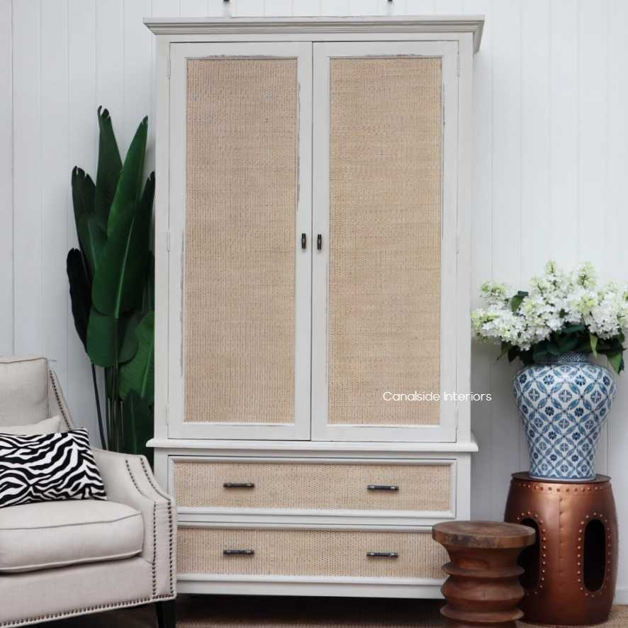 Natural light accentuating the wardrobe's texture and color nuances, highlighting the aesthetic appeal of distressed stone and natural rattan.