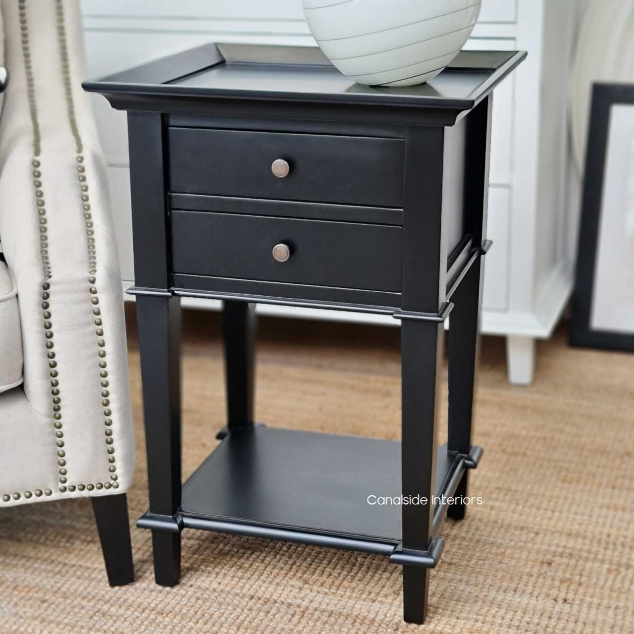 Angled view of the side table, emphasizing the sleek black finish and the practical bottom shelf for additional storage.