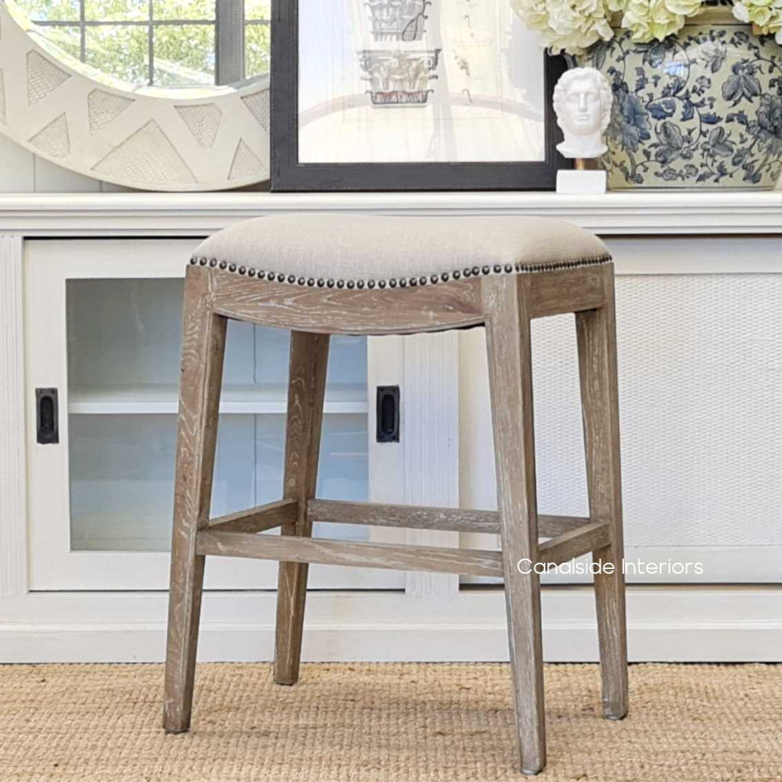 Angled view of the Mila II Stool, emphasizing the harmonious blend of cream upholstery with the natural beauty of the weathered oak base for a timeless kitchen appeal.