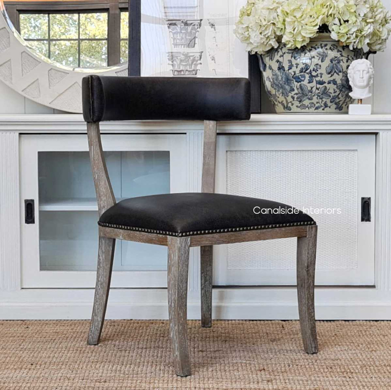 The Sainz Chair's weathered oak legs complement a coastal-themed lounge room, merging comfort with Canalside Interiors' chic design