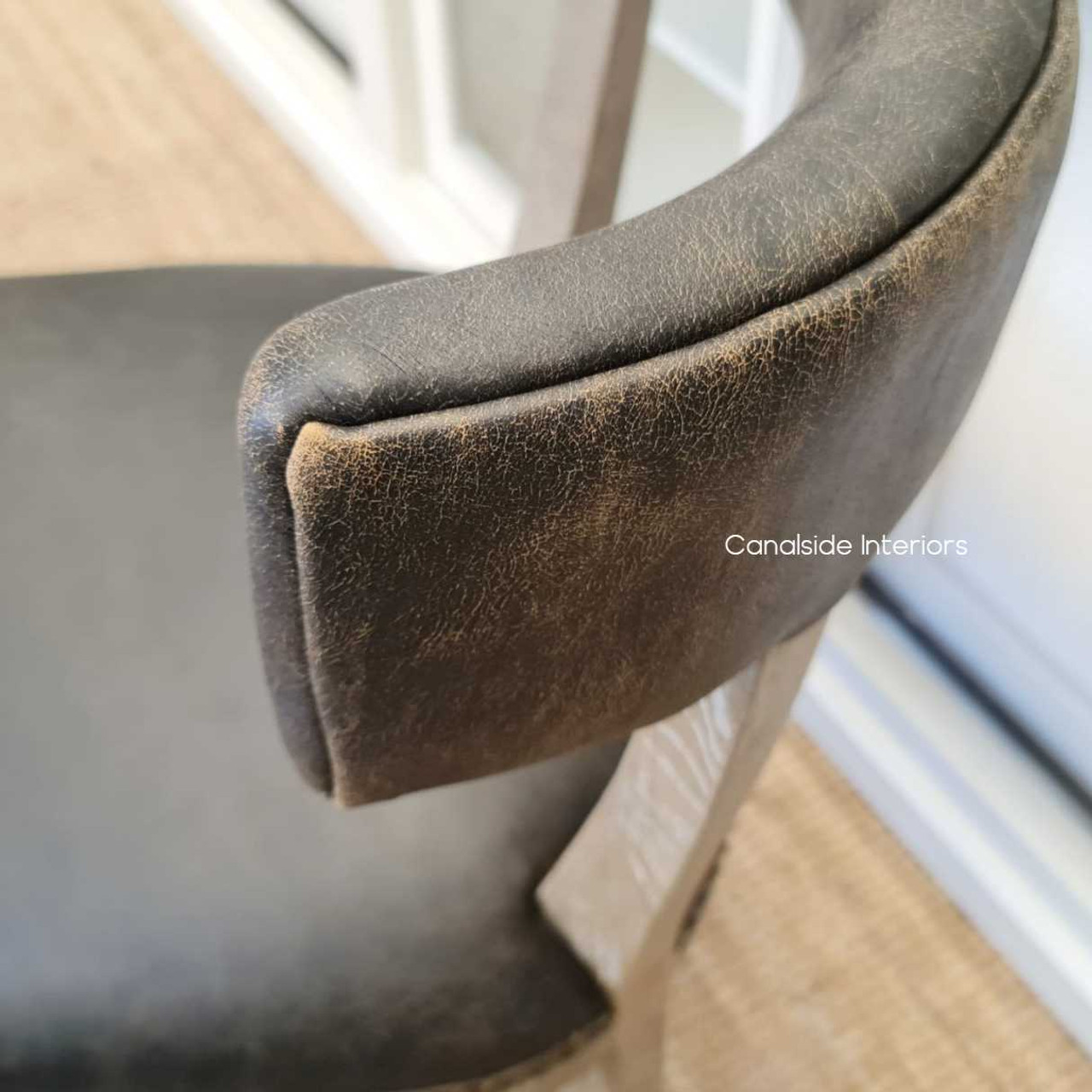 Aged leather Sainz Chair with its distinctive espresso tone, brings a classic yet modern touch to a stylish dining room - Canalside Interiors