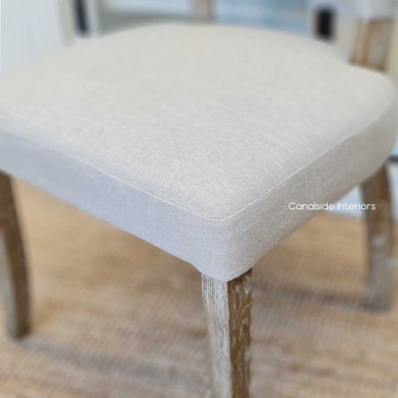 Detail shot of the Mimi Dining Chair's seat, emphasizing the comfort and quality of its cream upholstery.