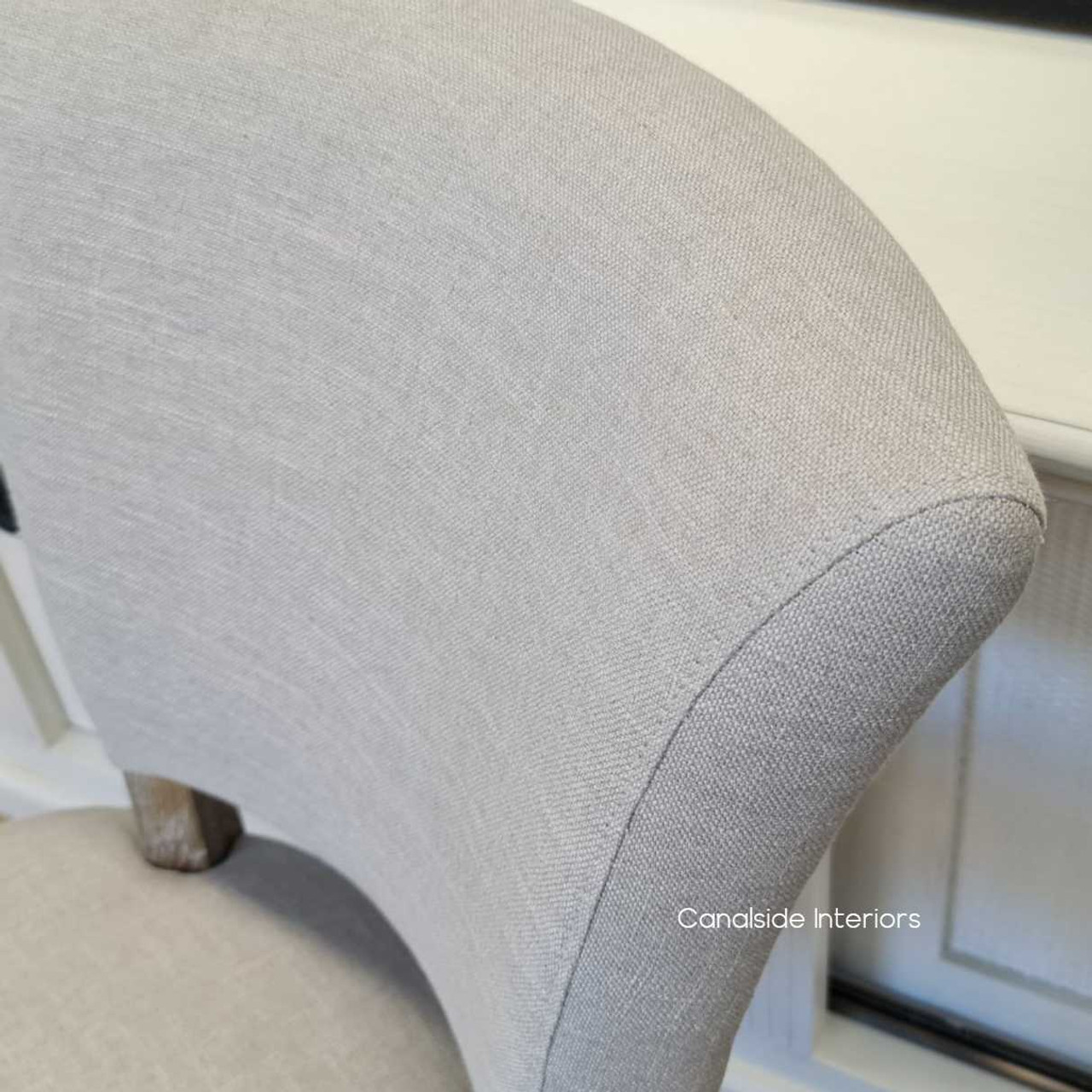 View of the Mimi Dining Chair, focusing on the chair's elegant silhouette and the fine detailing of its upholstery.