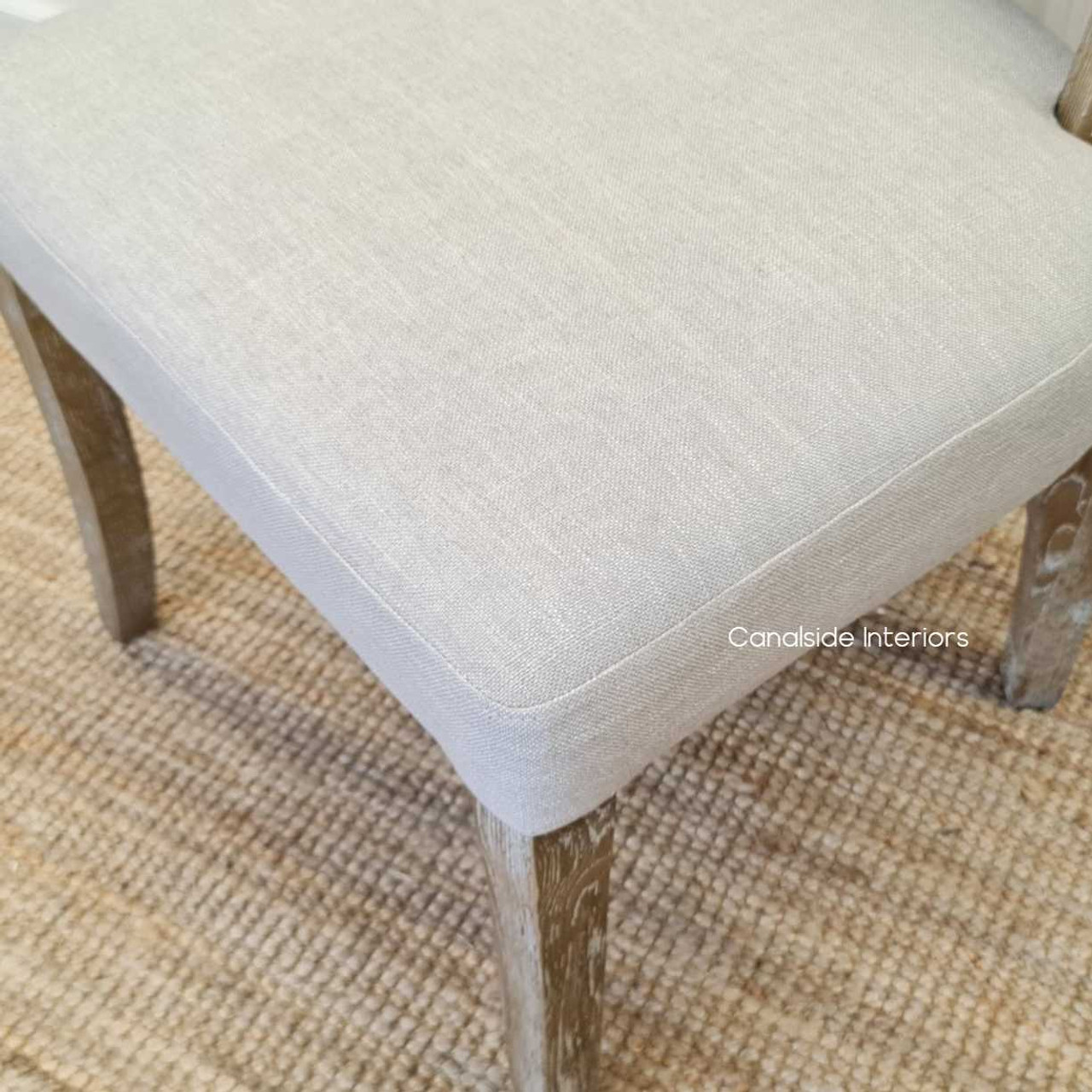 Detail shot of the Mimi Dining Chair's seat, emphasizing the comfort and quality of its cream upholstery.