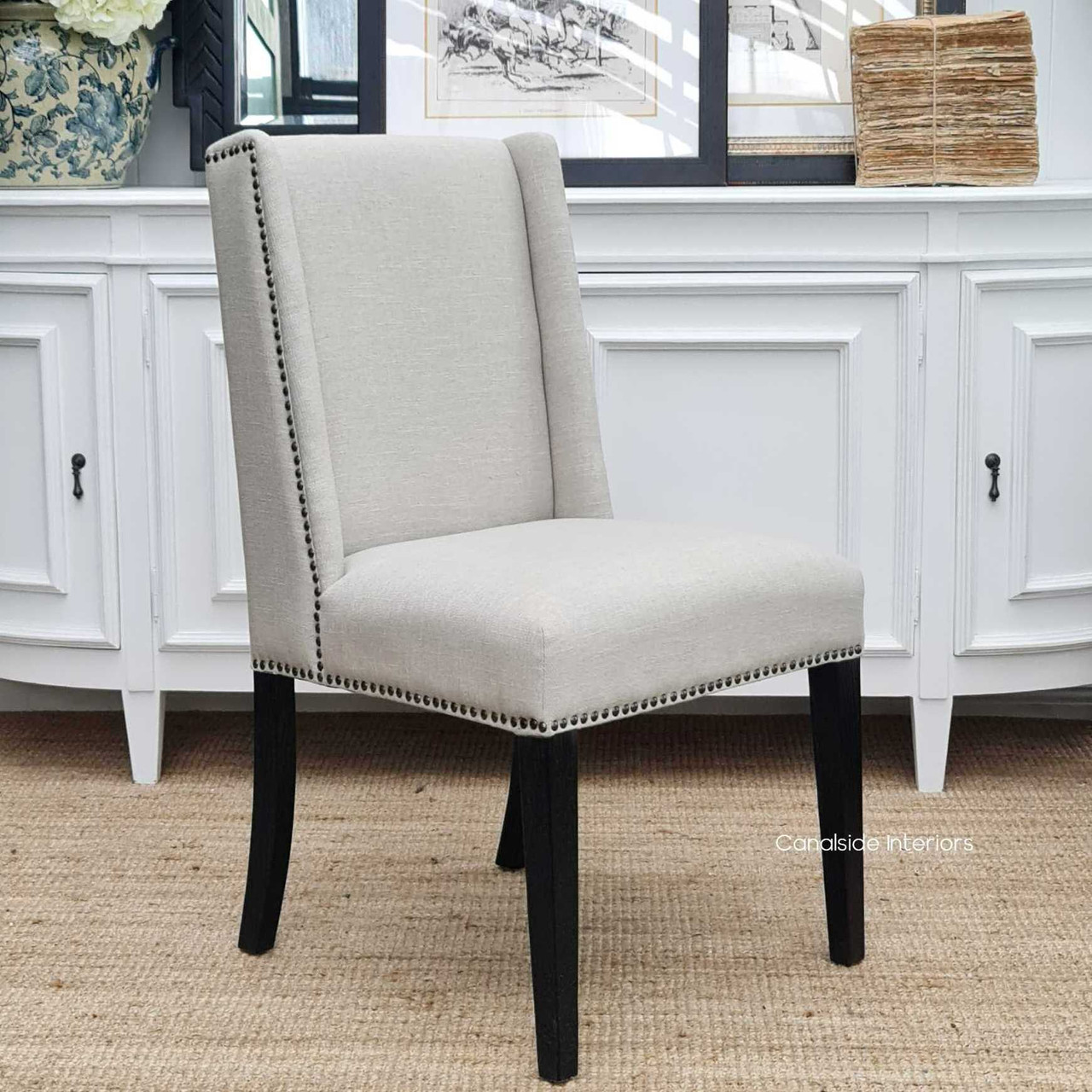 Frontal view of the Leclerc Dining Chair at Canalside Interiors, showcasing its cream upholstery and textured black legs against a modern Hamptons-style dining room backdrop.