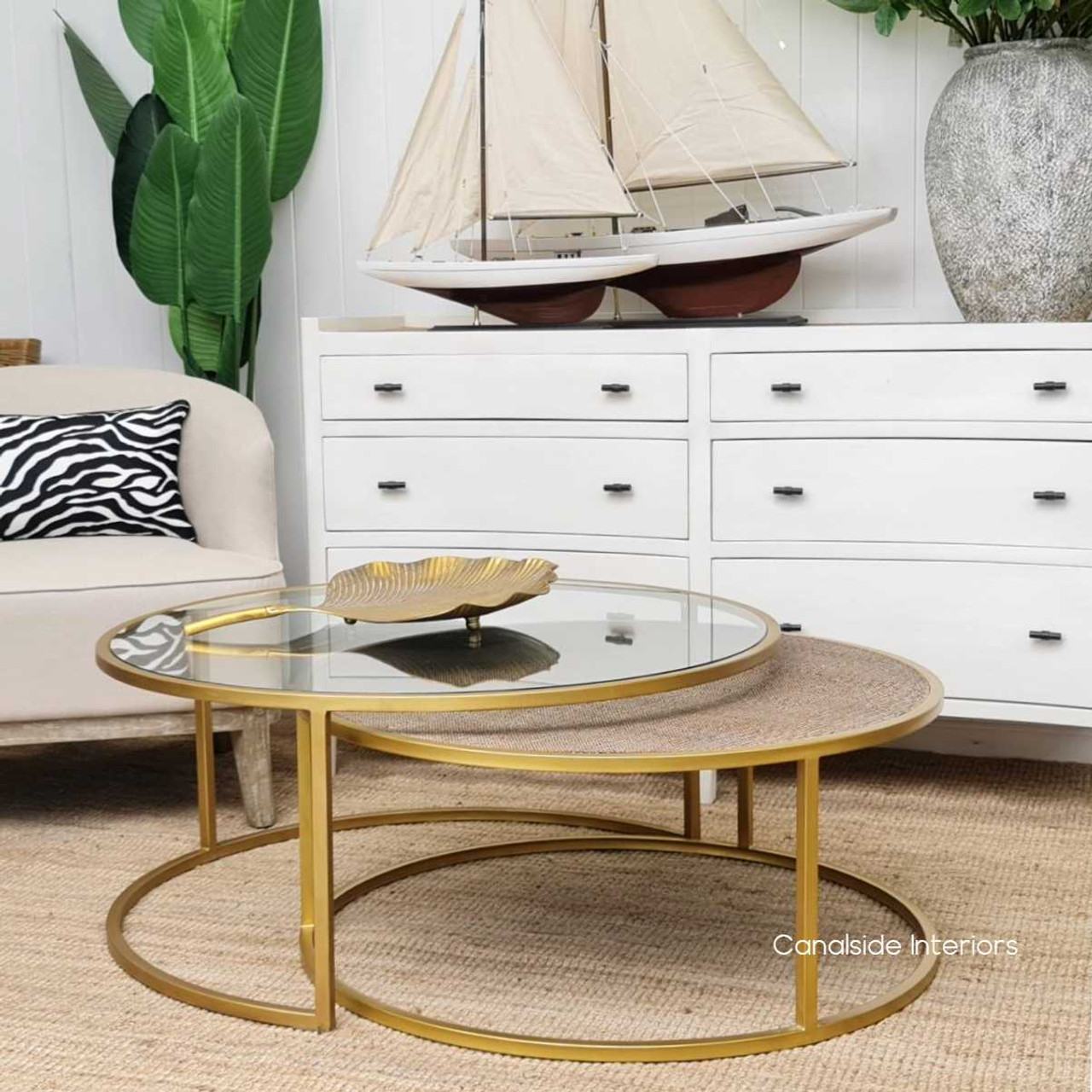 Introduce timeless sophistication to your living room with the gold-framed Knox Plantation Coffee Tables, featuring tempered glass and rattan surfaces – Canalside Interiors