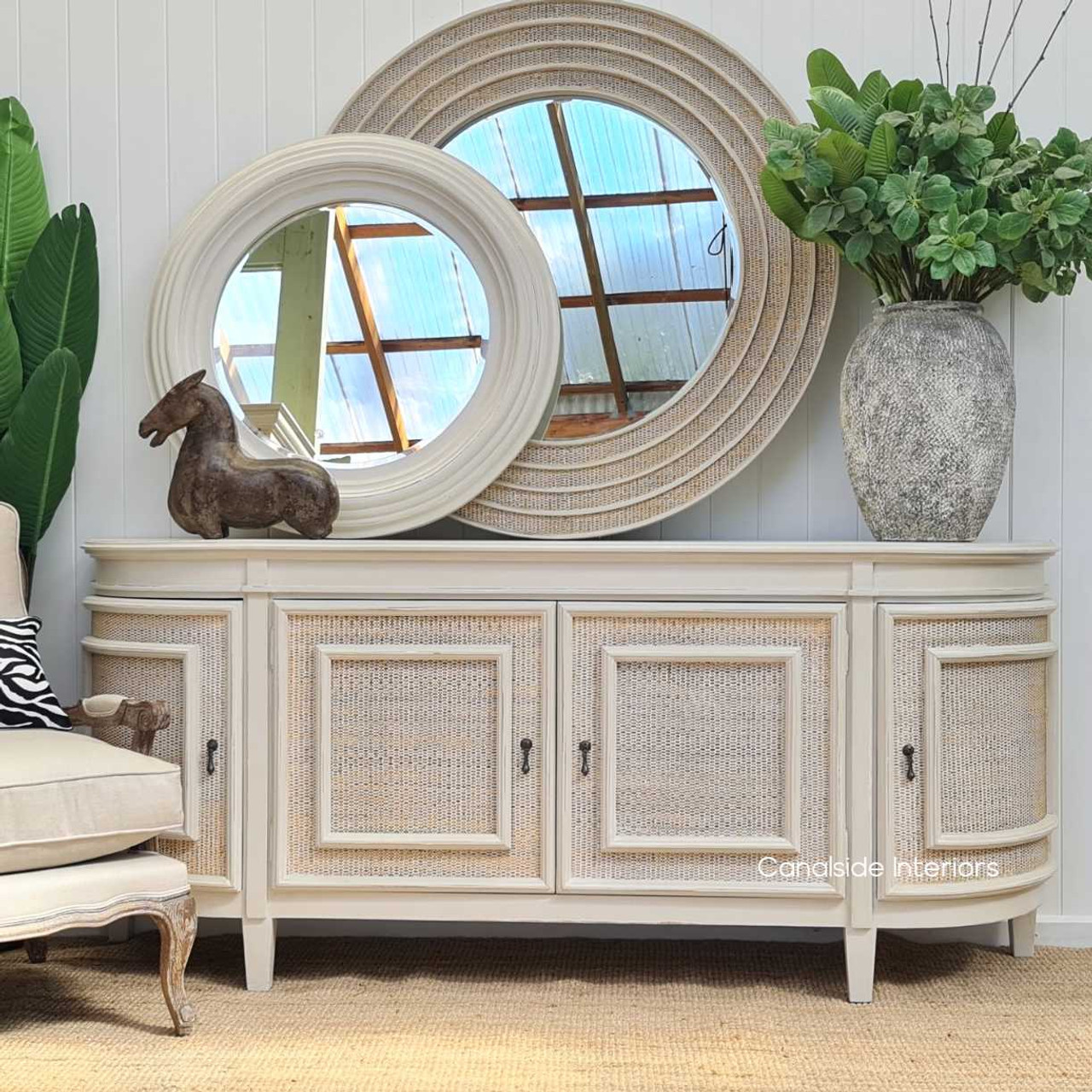 In the living room, the Francia Sideboard’s distressed stone and rattan finish by Canalside Interiors offers a stylish organization, resonating with coastal charm.