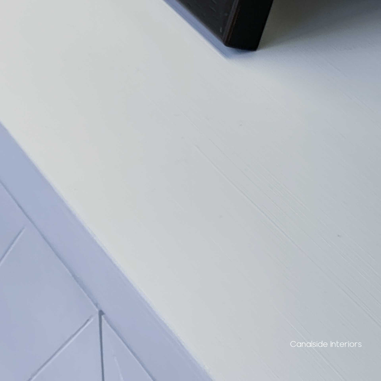 This four-door herringbone sideboard in distressed white by Canalside Interiors offers a stylish storage solution for any classical decor enthusiast.