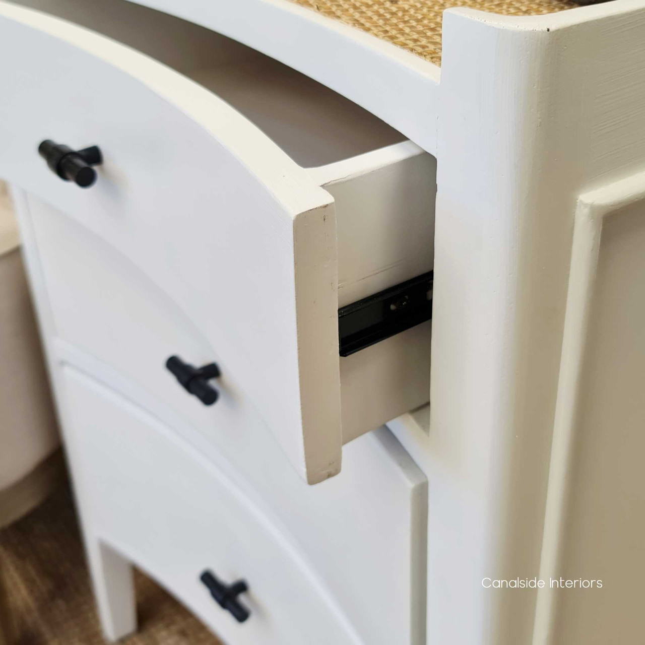 Angled view of the bedside, emphasizing the elegant concave design and the practical drawers on smooth metal runners.