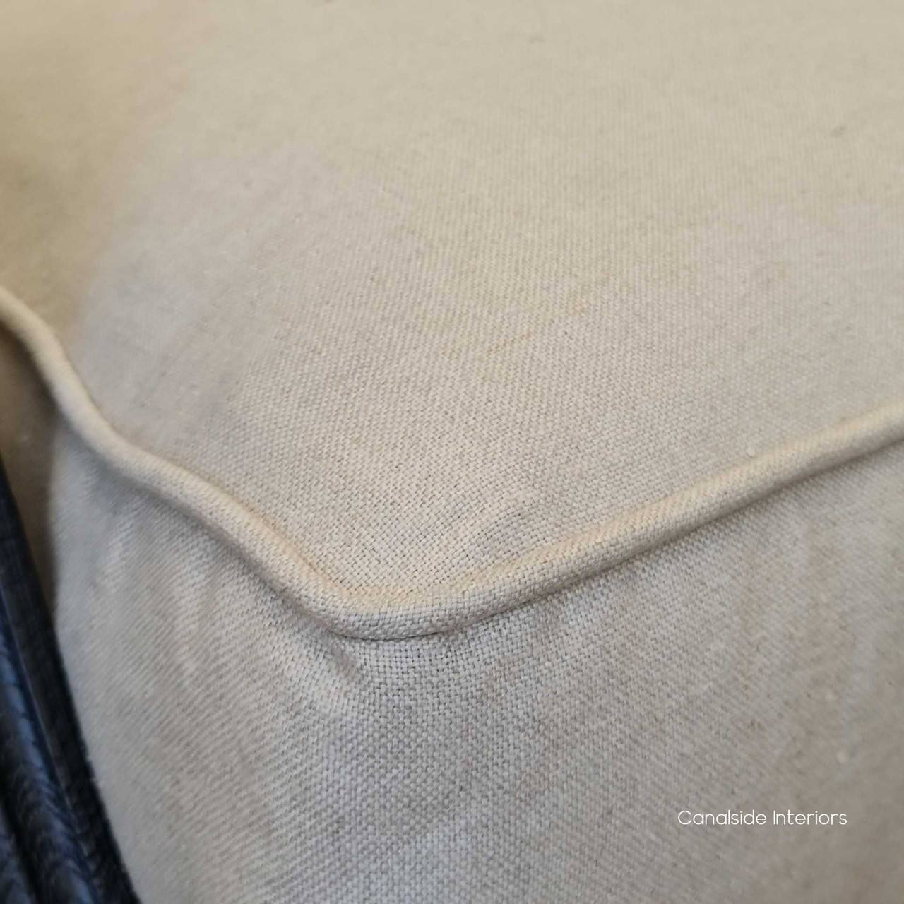 Detail focus on the cream linen upholstery's texture, underlining the armchair's high-quality materials and comfort.