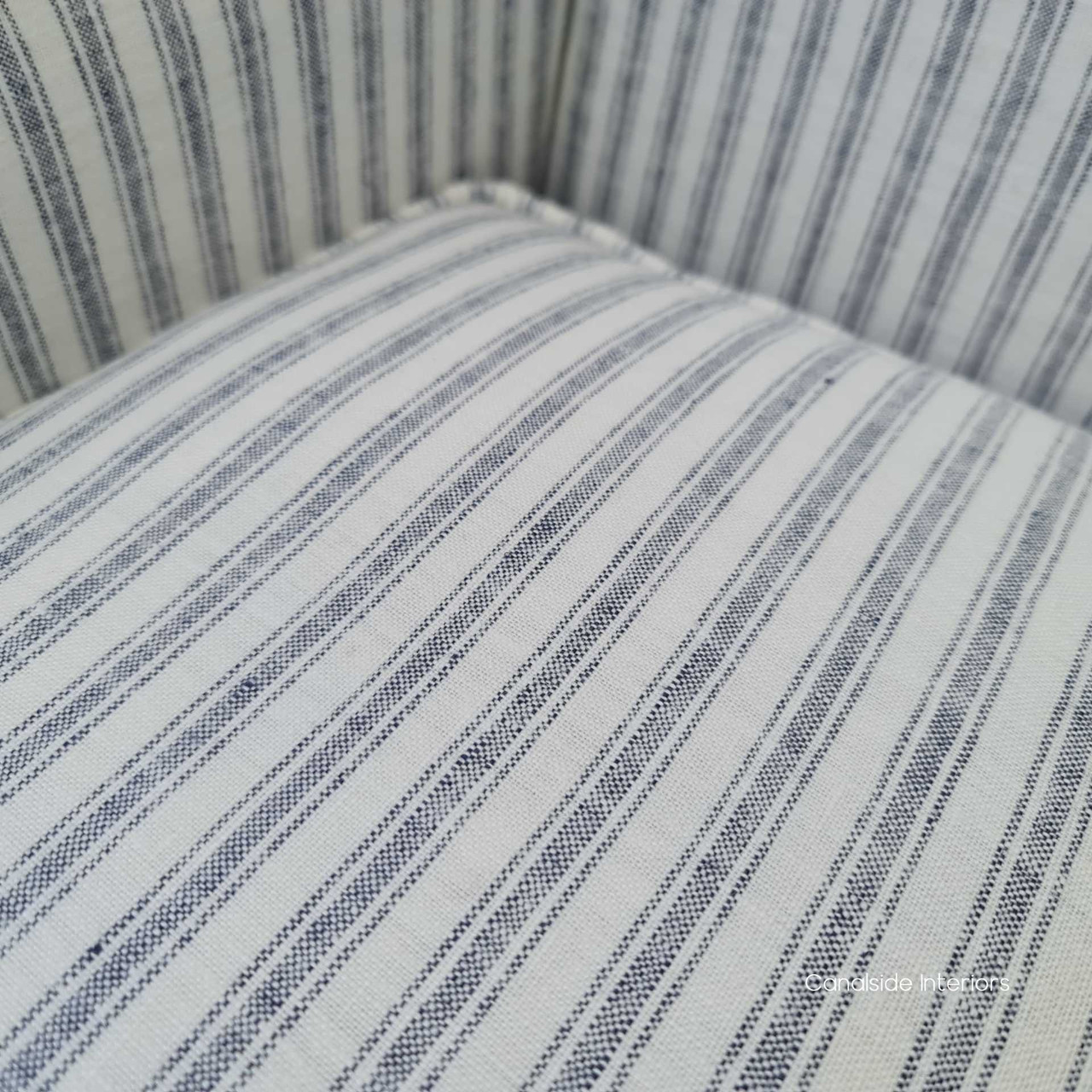 The armchair under soft lighting, accentuating the blue stripes and creating a serene, inviting atmosphere.