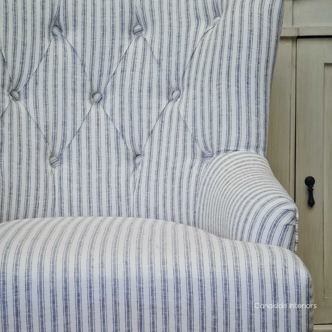 Elegant Ascott Armchair with tufted button detailing, providing a classic touch to a modern coastal living room.