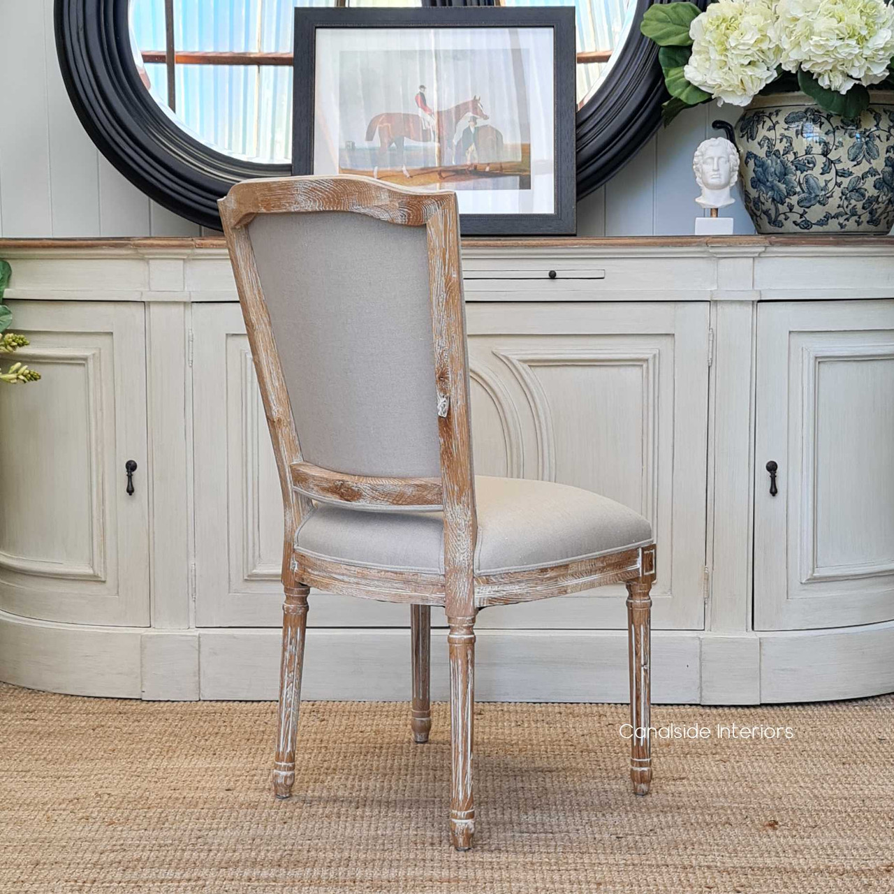 The cream linen-upholstered Knightley Chair from Canalside Interiors brings a fresh, coastal vibe to your dining room with its limewash finish