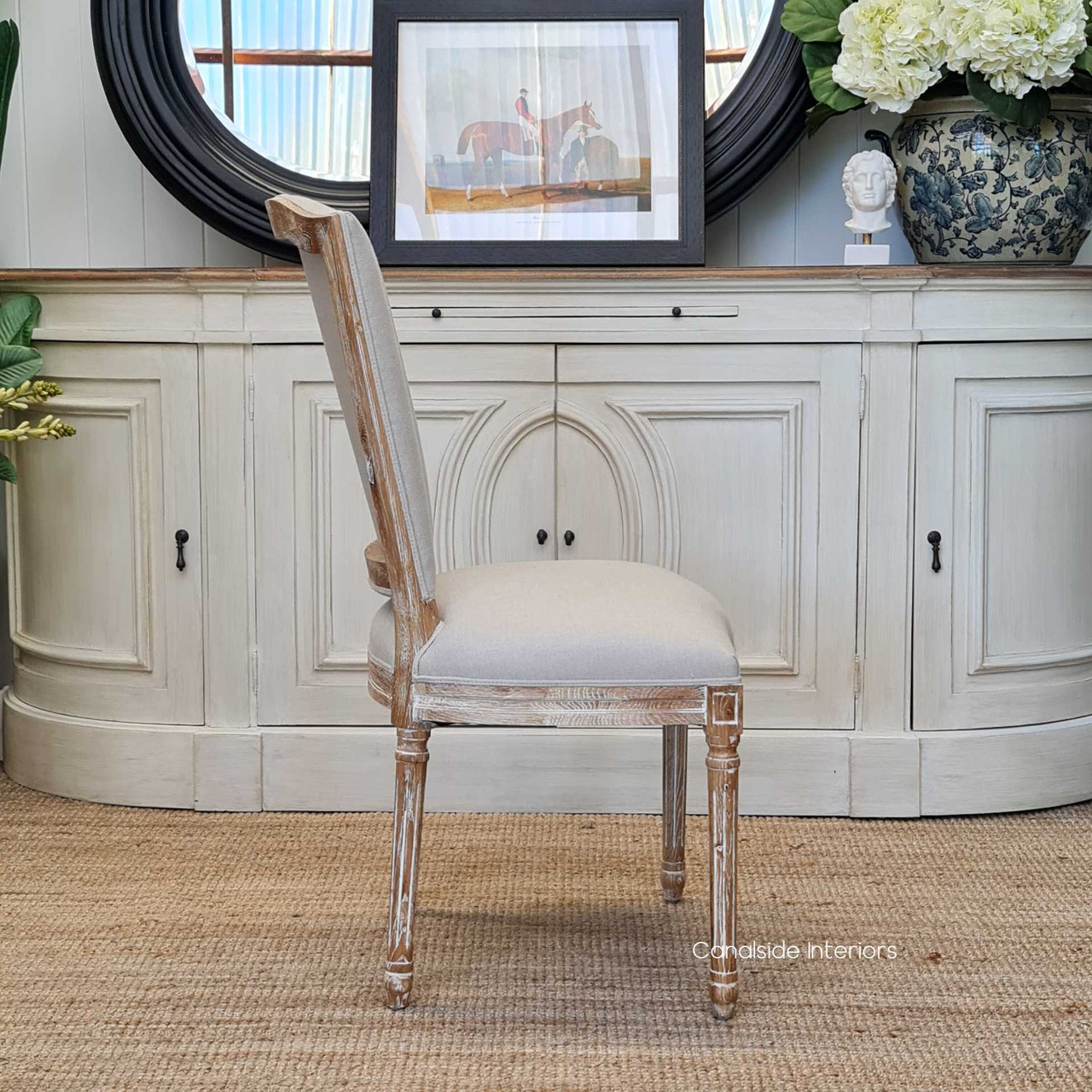 Settle into the classic charm of the Knightley Dining Chair by Canalside Interiors, featuring cream linen upholstery on a limewashed oak structure for a coastal dining ambiance