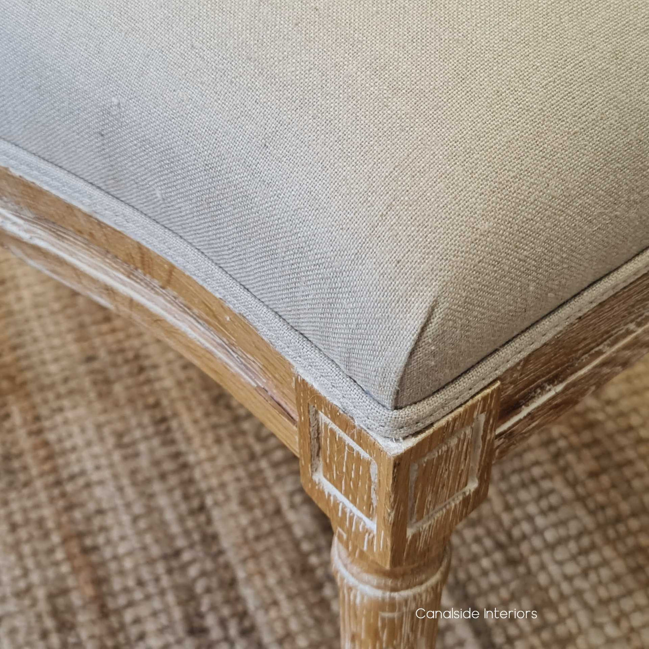 The Knightley Chair's cream linen seat, supported by a hand-carved oak frame, offers a blend of Hamptons elegance and contemporary comfort