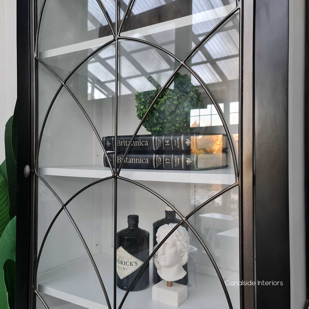 Close-up of the cabinet's glass display door, highlighting the intricate iron detailing that adds a gothic touch to the modern home.